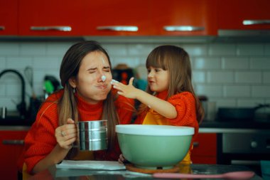 Küçük kız ve annesi mutfakta yemek pişirirken unla oynuyorlar.