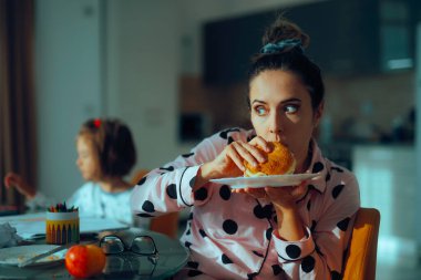 Çocuk resim çizerken anne hemen sandviç yiyor.