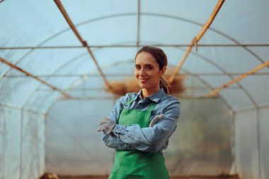 Kadın Çiftçi Bir serada duruyor Kolları çaprazlanmış gülümsüyor