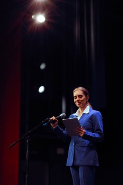Tablet tutan ve mikrofona konuşan kadın.