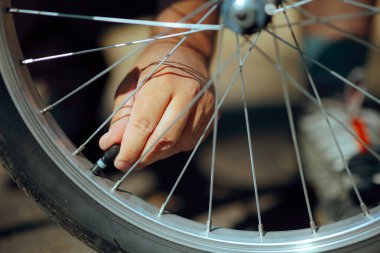 Bisikletçi motoru şişirmek için bisiklet tekerleğinin valfini söker