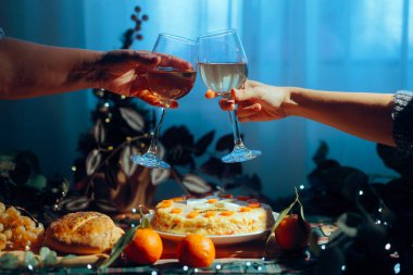 İnsanlar yemek masasında beyaz şarap kadehlerini tokuşturur.