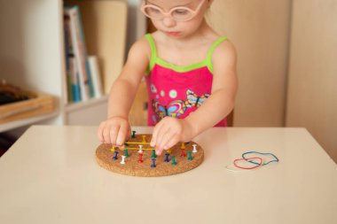 A girl with Down syndrome trains fine motor skills. Stretch