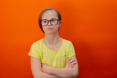 Happy girl with Down syndrome. Having fun, laughing. Funny pigtails. Studio. Portrait on a orange background