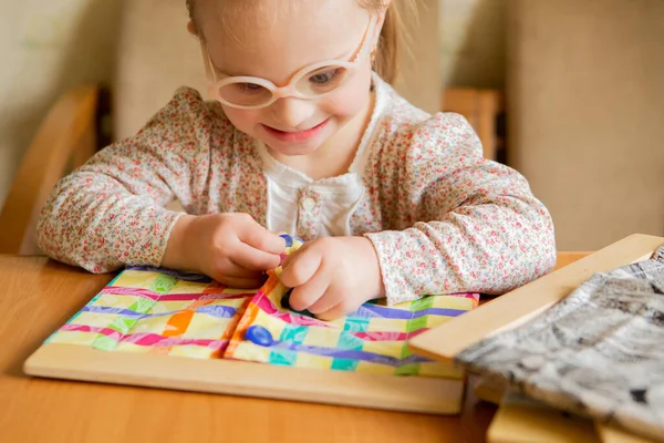 A girl with Down syndrome develops fine motor skills. Self-service skills Buttons