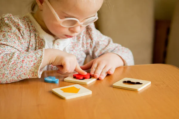 A girl with Down syndrome develops fine motor skills. learning to assemble puzzles