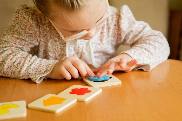 A girl with Down syndrome develops fine motor skills. learning to assemble puzzles