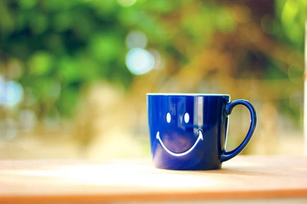 smile on blue mug coffee cup against blur bokeh abstract background