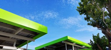 Geometrik kare şekilli çatı. Çelik yapıda yeşil üst renk. Mavi gökyüzünde beyaz bulut.