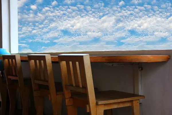 wooden chairs and bar counter with blue sky white cloud