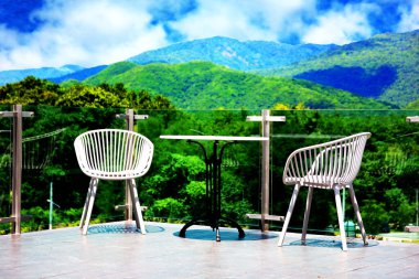 Terasa kurulmuş sandalyelerin manzara manzarası için çim duvarları var.