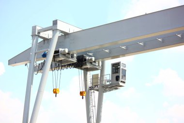 Alçak açılı açılı açıyı kapat. Mavi gökyüzüne karşı vinç kontrol odası ile birlikte iki elektrik direği kirişe ayarlı.