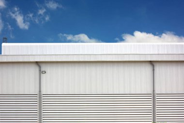Metal kıvrımlı duvar çimentosu kullanarak mimari tasarım fabrikası deposu. Mavi gökyüzüne karşı kıvrımlı doku oluşumu ve havalandırma delikleri