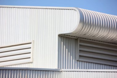 Mimari tasarım eğrisi şekli kıvrımlı duvar geometrik binası. Fabrika deposu, mavi gökyüzüne karşı ilgi uyandırmak için dokularla kaplanmış.