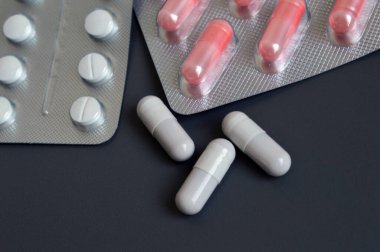 Gri arka planda haplar ve kapsüller, ilaçlar, vitaminler