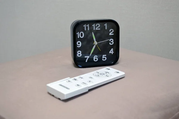 Relógio Preto Senta Otomano Junto Cama Quarto Com Controle Remoto — Fotografia de Stock