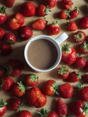Tahta Masa üzerinde Sütlü ve Taze Çilekli Bir fincan Kahve - Dikey Düz Yatay