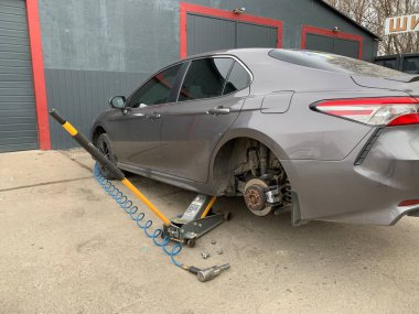 Araba serviste, tekerlek tamiri. Krikonun üstündeki araba, tekerlek değiştiriyor. Konsept: lastik denemesi, volkanizasyon, lastik değiştirme. Kiev bölgesi, Irpen, oto tamirhanesi, 18 Mart 2023