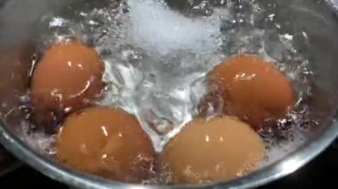 Kaynar suda tavuk yumurtası, yakın plan. Tencerede tavuk yumurtasıyla kaynar su. İndüksiyon sobasında yemek pişirmek..