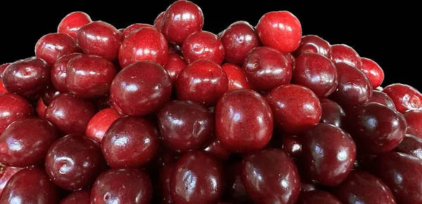 一堆成熟的樱桃放在盘子里 用黑色隔开 在黑暗的背景上有很多勃艮第樱桃 成熟的红色浆果 成熟的水果 — 图库照片