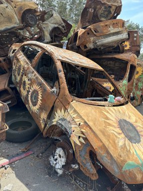 Yanmış bir arabada çocukların yumuşak oyuncağı. Araba, askeri bir merminin patlaması sonucu hasar gördü. Havaya uçurulmuş ve yanmış arabalar. Ukrayna, Irpin, 6 Haziran 2023