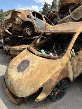 Yanmış bir arabada çocukların yumuşak oyuncağı. Araba, askeri bir merminin patlaması sonucu hasar gördü. Havaya uçurulmuş ve yanmış arabalar. Ukrayna, Irpin, 6 Haziran 2023