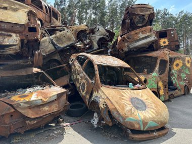 Yanmış bir arabada çocukların yumuşak oyuncağı. Araba, askeri bir merminin patlaması sonucu hasar gördü. Havaya uçurulmuş ve yanmış arabalar. Ukrayna, Irpin, 6 Haziran 2023