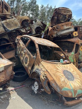 Yanmış bir arabada çocukların yumuşak oyuncağı. Araba, askeri bir merminin patlaması sonucu hasar gördü. Havaya uçurulmuş ve yanmış arabalar. Ukrayna, Irpin, 6 Haziran 2023