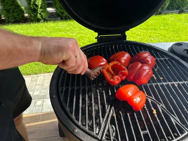赤ピーマンのグリル 庭でグリルし 石炭の上で野菜を調理する 火で野菜を炊く男 — ストック写真