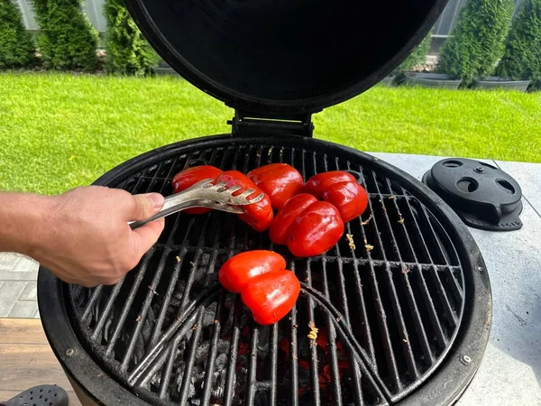 赤ピーマンのグリル 庭でグリルし 石炭の上で野菜を調理する 火で野菜を炊く男 — ストック写真