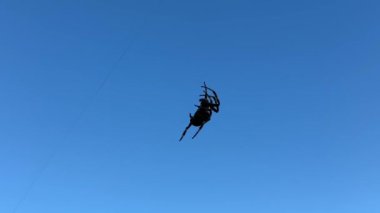 Gökyüzünün arka planında ipi olan siyah elbiseli bir adam.