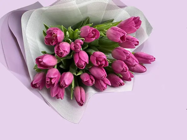 Bouquet of pink tulips in paper packaging. Spring flowers on a pink background, tulips.