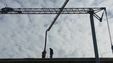 İnşaatçılar montaj vincinin arka planına karşı çalışıyorlar. Bir inşaat alanındaki işçiler, yüksek binaların inşaatının arka planına karşı. Lviv, St. Melnik, 20 Şubat 2024