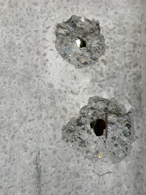 Arka plan dokusu: Betonda kurşun yarasından kaynaklanan bir delik. Beton duvar bir kurşunla delinmiş. Duvarda bombardıman izleri var, yakın plan..