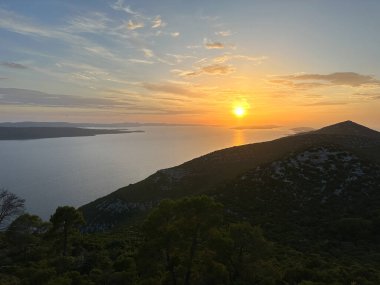 Gün batımı denizin ve dağların ardında. Deniz suyunda batan güneşin yansıması, dağdan görüş..