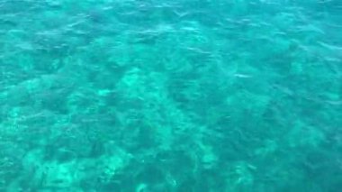 Adriyatik Denizi 'nin şeffaf suları, yakın plan. Güneşin berrak turkuaz deniz suyundaki yansıması.