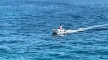 Tekne dalgaları denizin arka planına doğru keser. Bir motorlu tekne mavi denizde yelken açar. Hırvatistan açıklarındaki Adriyatik kıyısında tatiller, Preko adası, 27 Haziran 2024