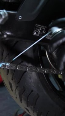 Motosiklet zincirini temizlemek için fırça kullanıyor. Böylece kir ve kirden arınmış oluyor.