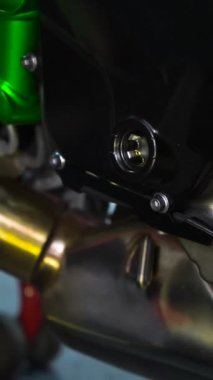 Canlı yeşil egzoz borusundan oluşan bir motosiklet motorunun detaylı çekimi, otomotiv makinelerinin karmaşık tasarımını gözler önüne seriyor.
