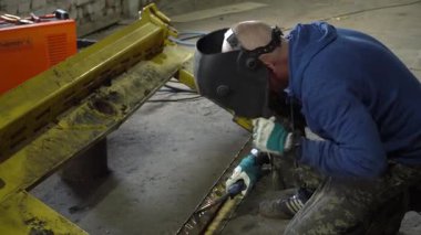 Yetenekli bir kaynakçı, bir atölyede titizlikle metal üzerinde çalışıyor ve olağanüstü hünerlerini sergiliyor.