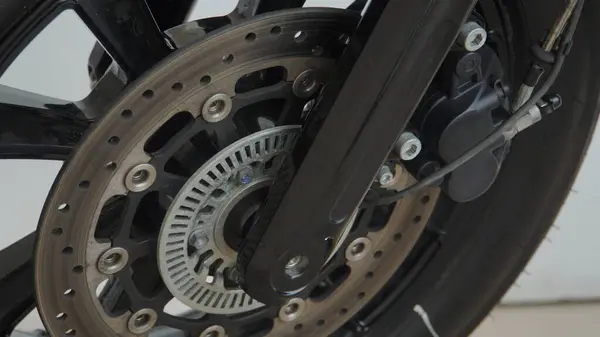 Modern mühendisliğin hassasiyetini gösteren, motosiklet fren parçalarının ve tekerleğin detaylı bir görüntüsü.