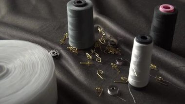 Renkli dikiş iplikleri, çengelli iğneler ve kumaş yüzeyinde ustalıkla düzenlenmiş gerekli aletlerden oluşan bir koleksiyon.