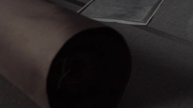 Büyük rulo bir mat kağıdının yakından görüntüsü yavaşça ve dikkatlice dokulu bir yüzeye açılıyor.