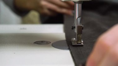 Kumaş olarak çalışan bir dikiş makinesinin detaylı bir yakın çekim görüntüsü özen ve hassasiyetle birleştirilir.