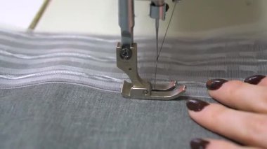 Dikiş makinası, kumaşı karmaşık bir şekilde dikiyor, ustalık ve sanatsal yeteneklerini güzelce sergiliyor.