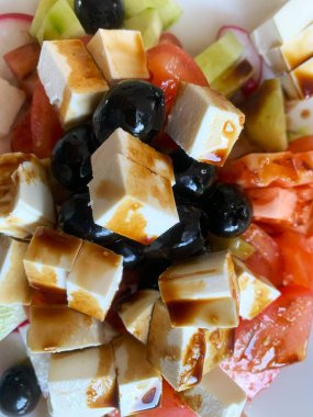 Keskin peynirli, tuzlu zeytinli ve çeşitli sebzeli taze Yunan salatasının tadını çıkarın.