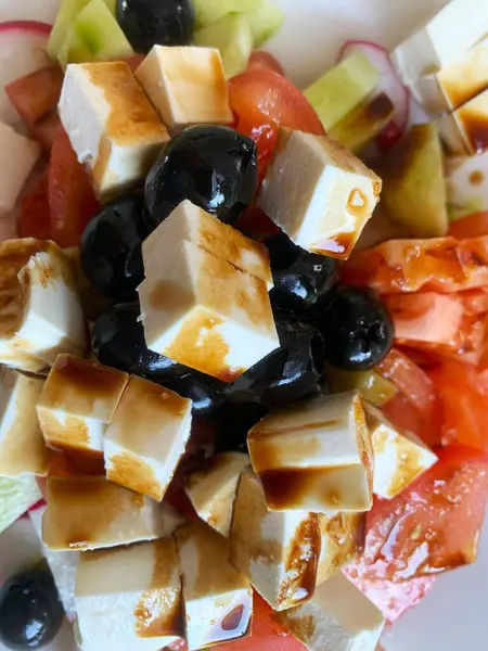 Keskin peynirli, tuzlu zeytinli ve çeşitli sebzeli taze Yunan salatasının tadını çıkarın.