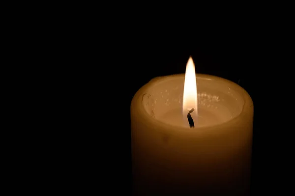 close-up of a burning candle wick in the dark. The flame of burning candles on a dark background.