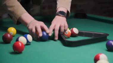 Bir adamın eli bilardo oynadıktan sonra renkli topları toplar ve yeni bir oyun hazırlar..