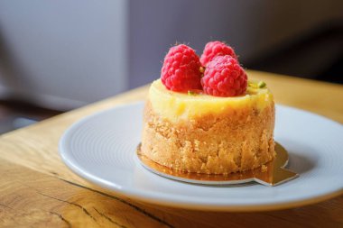Beyaz tabakta ahududulu cheesecake. Bir parça lezzetli ahududulu cheesecake..